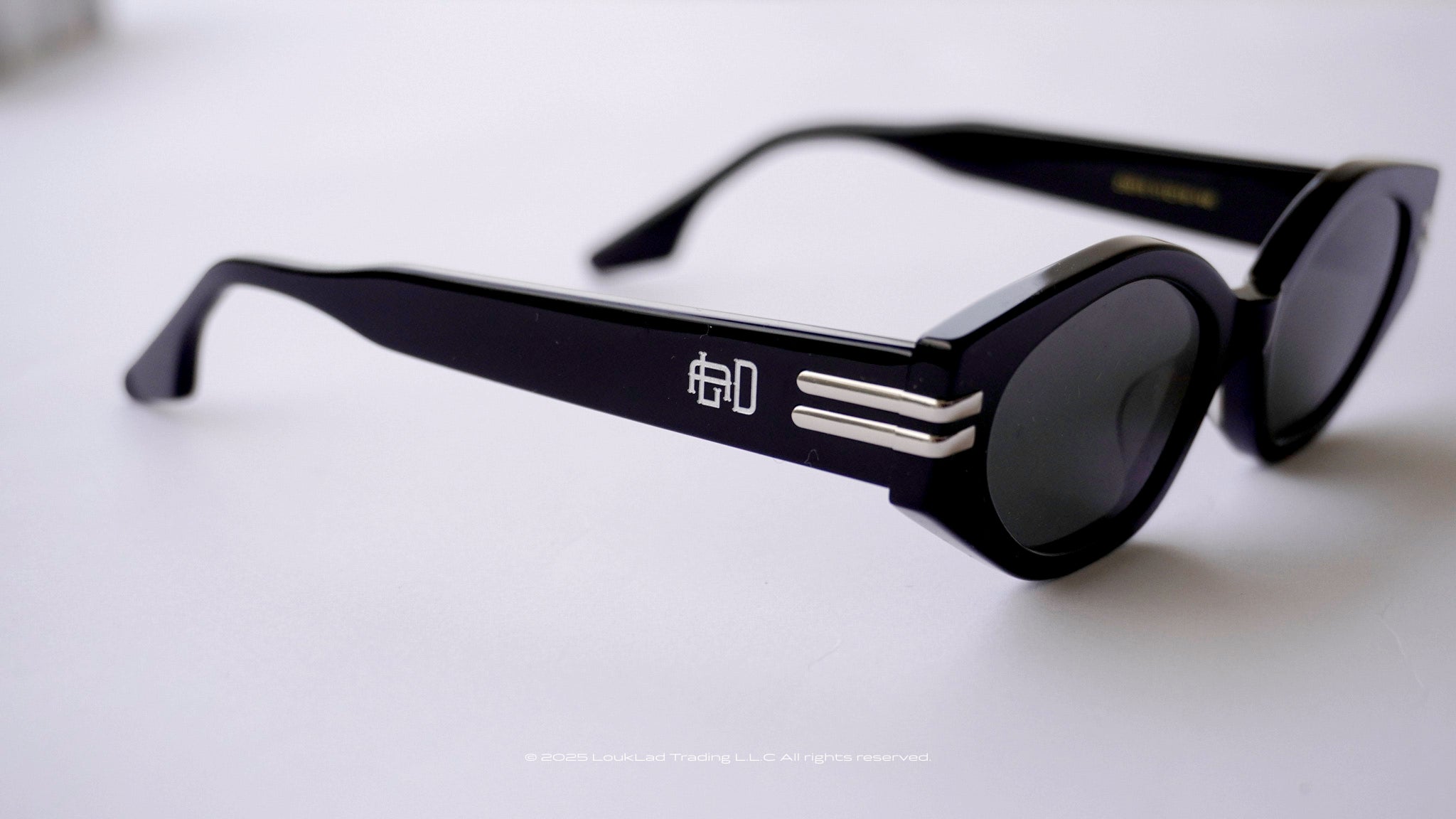 Black sunglasses with a Engraved logo on a light gray background