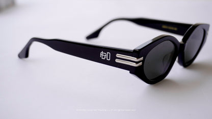 Black sunglasses with a Engraved logo on a light gray background